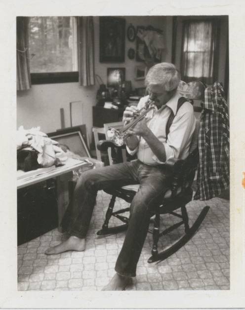 man playing trumpet sitting on chair